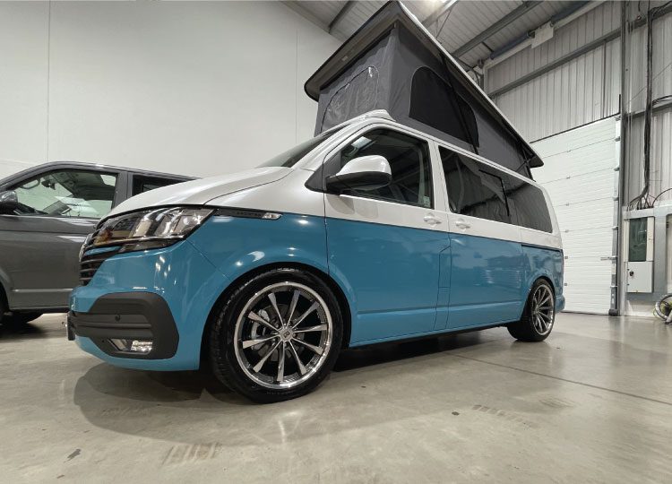 Blue and white VW campervan with pop top roof and black windows