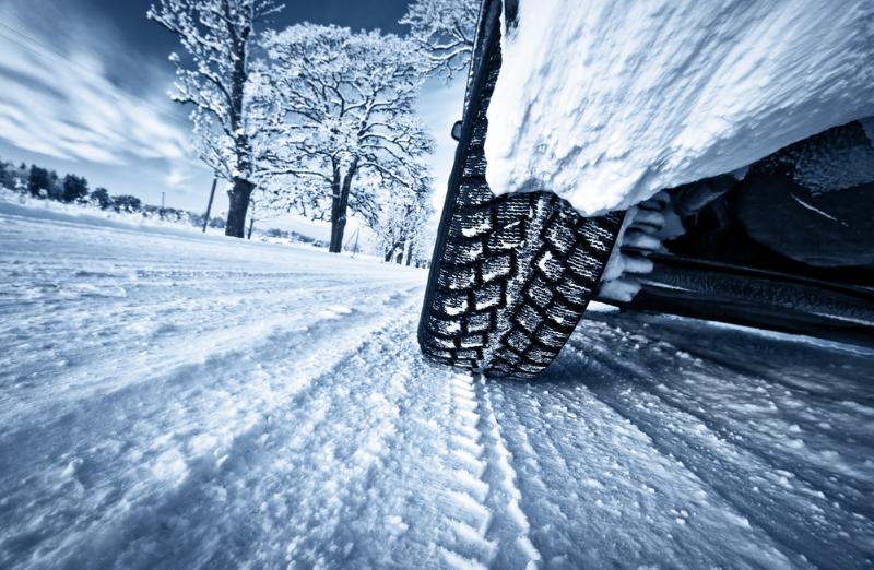 Underneath the campervan looking at the tyre tread on the snowy road.